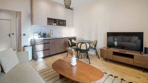 A modern living room with a sofa, a coffee table, a TV, and a dining area with chairs and a table. - 11.Appart 4Pers#1 Bedroom #Père Lachaise #Nation (Paris)