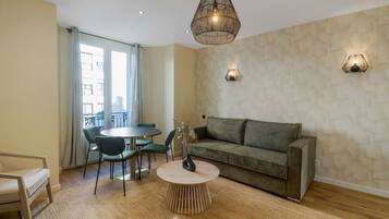 Una sala de estar moderna con una mesa redonda, un sofá gris y una zona de comedor con una mesa y sillas redondas.
