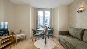 Ein modernes Wohnzimmer mit Fernseher, Sofa, Esstisch und Stühlen.