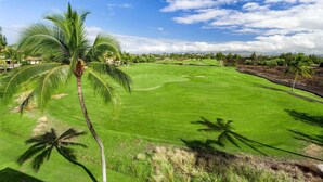 A golf course with a clear sky, palm trees, and a well-maintained green field. - 🏖️Top-Floor Waikoloa Condo Overlooking Golf Course | Walk to A-Bay & Shops | Fairway Villas A31 (Waikoloa)