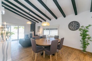 Un coin repas avec une table ronde, des chaises, une horloge et une plante en pot.