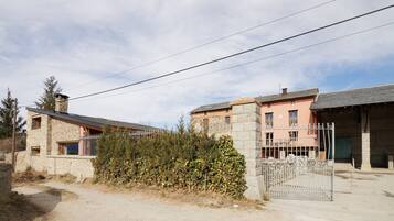 A rustic stone building with a metal gate, a dirt path, and a clear sky.