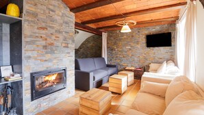 Ein gemütliches Wohnzimmer mit Kamin, einem grauen Sofa, Holzfußscheinen und einem weißen Sofa.