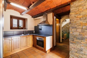 A kitchen with wooden cabinets, a stove, and a brick wall.