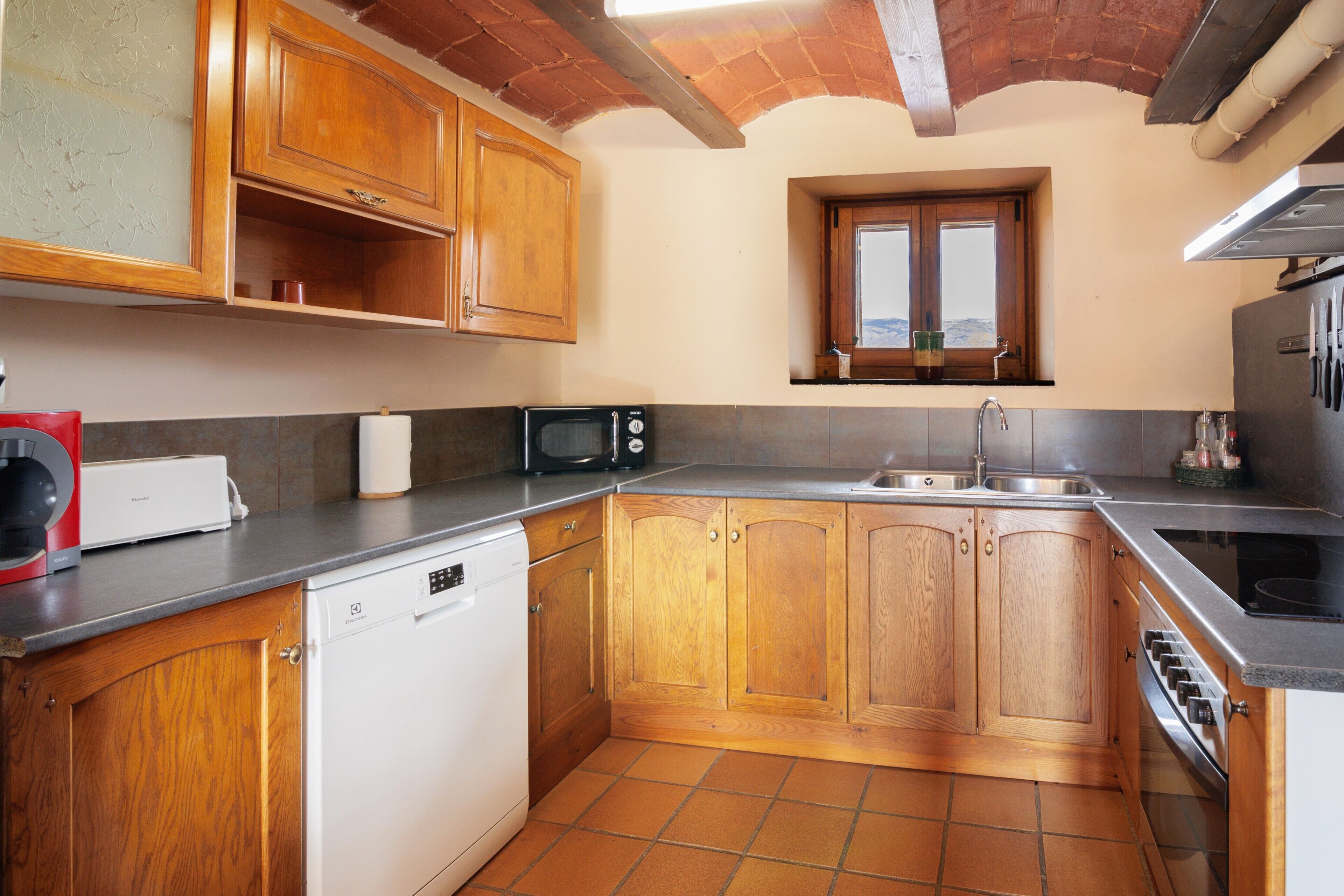 Une cuisine avec des meubles de rangement en bois, un lave-vaisselle, un four à micro-ondes et un évier.