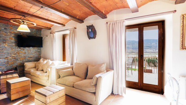 Ein Wohnzimmer mit einer Couch, Holzmöbeln, einem Fernseher und Blick durch ein Fenster.