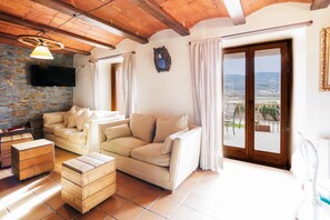 Un salon avec un canapé, des meubles en bois, un téléviseur et une vue par la fenêtre.