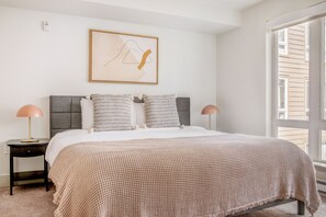 Relax in a serene bedroom with a large bed, framed artwork, and modern bedside lamps.