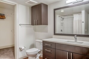 Bathroom features a toilet, vanity with mirror, and shower with glass door.