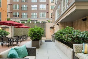 Relax in style with a seating area, potted plants, and a shaded spot under a red umbrella.