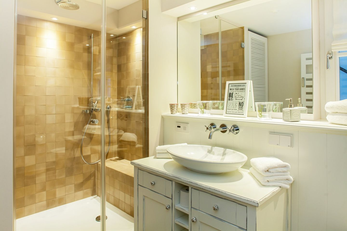 A modern bathroom with a glass-enclosed shower, a large mirror, and a white sink.