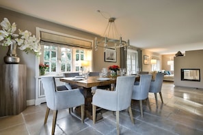 A dining area with a wooden table, grey upholstered chairs, and a chandelier. - Klenterhüüs - Klenterhüüs - Hochwertig und Exklusiv Ausgestattetes Ferienobjekt (Sylt-Ost)