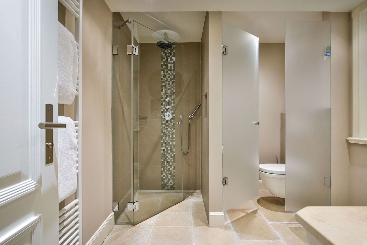 A modern bathroom with a glass-enclosed shower, a toilet, and a sink.
