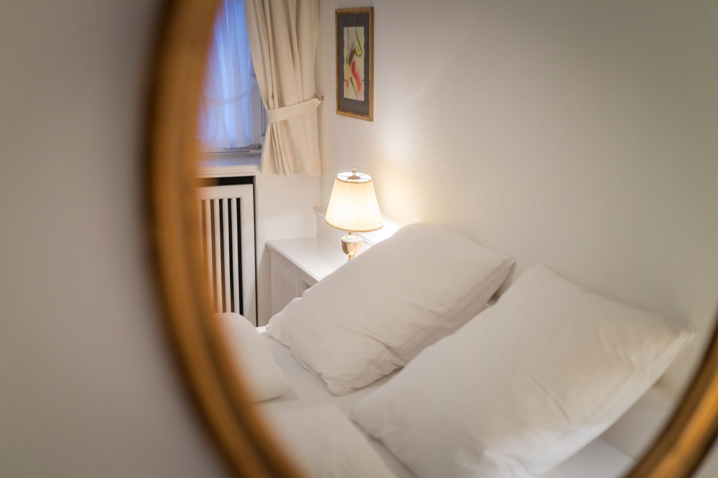 A bedroom with a bed, a bedside table with a lamp, and a radiator.