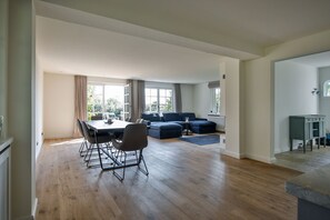 A spacious living room with a dining area, large windows, and a view of the outdoors.