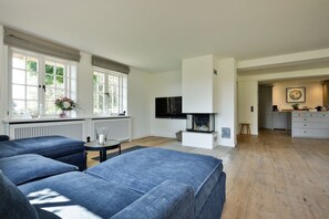 A modern living room with a fireplace, a dining area, and a kitchen.