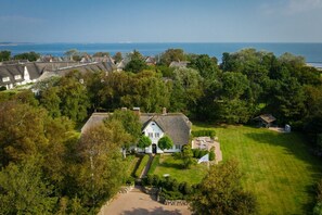 A large estate with a central house surrounded by lush gardens and a view of the sea.