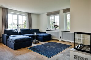En moderne stue med en hjørnesofa, et lille rundt bord og en blå måtte.