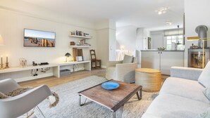Un salon moderne avec un téléviseur à écran plat, des  étagères, une table basse et un canapé.