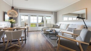 Una sala de estar moderna con comedor, ventanas grandes y vistas al exterior.