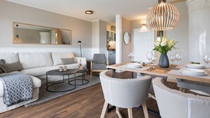 Una sala de estar moderna con un sofá, una mesa de centro y un comedor con una mesa dispuesta para cuatro comensales.