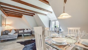 A dining area with a glass table, white chairs, and wine glasses. - Sharky Bay - Die Reetgedeckte, Gepflegte Anlage Liegt auf Einem ca. 2000 m² Großem Grundstück (Sylt-Ost)
