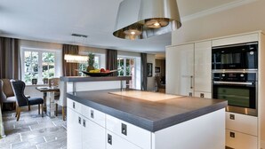 A modern kitchen with a central island, built-in appliances, and a dining area with a view.