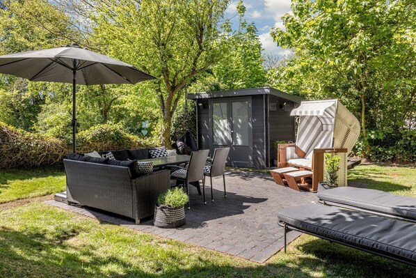 Un'area patio esterna con tavolo, sedie, divano e una zona salotto coperta.