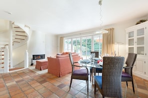 A spacious living area with a fireplace, a dining table set for four, and a comfortable seating arrangement.