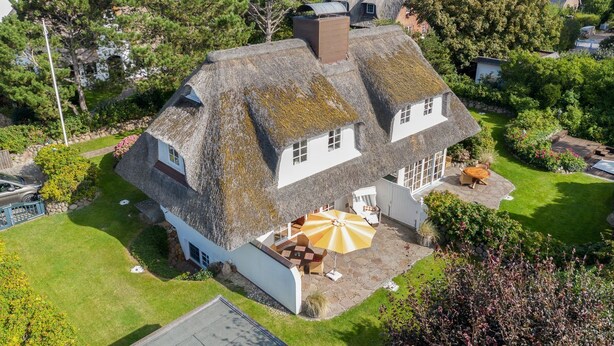 A thatched-roof house with a patio and outdoor seating area. - Luv Hüs - Luv Hüs - Geräumige Haushälfte in Keitum (Sylt-Ost)