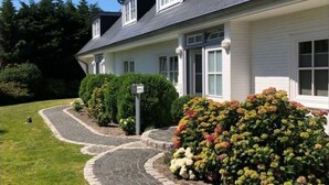 Una casa de dos pisos con entrada pavimentada y jardín cuidado.