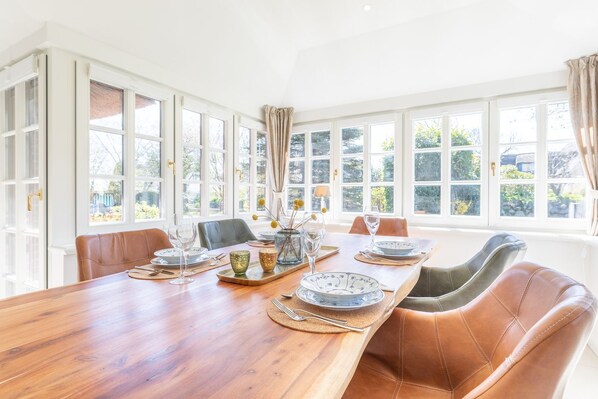 Comedor con una mesa de madera dispuesta para seis personas, rodeado de sillas de cuero.