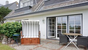 Un patio con un banco de madera, una mesa y sillas.