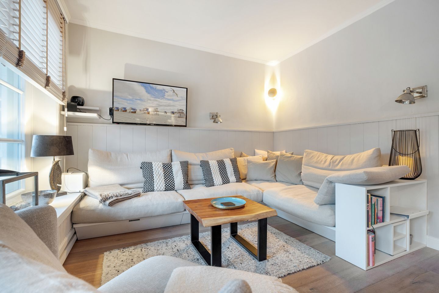 Een moderne woonkamer met een hoekbank, een salontafel en een boekenkast.