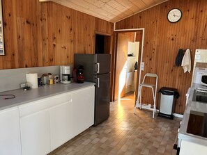 A kitchen with wooden walls, a stainless steel refrigerator, a coffee maker, and a trash bin. - Chalet 'Quartier Des Pêcheurs Réf 35' with Private Garden (Lège-Cap-Ferret)