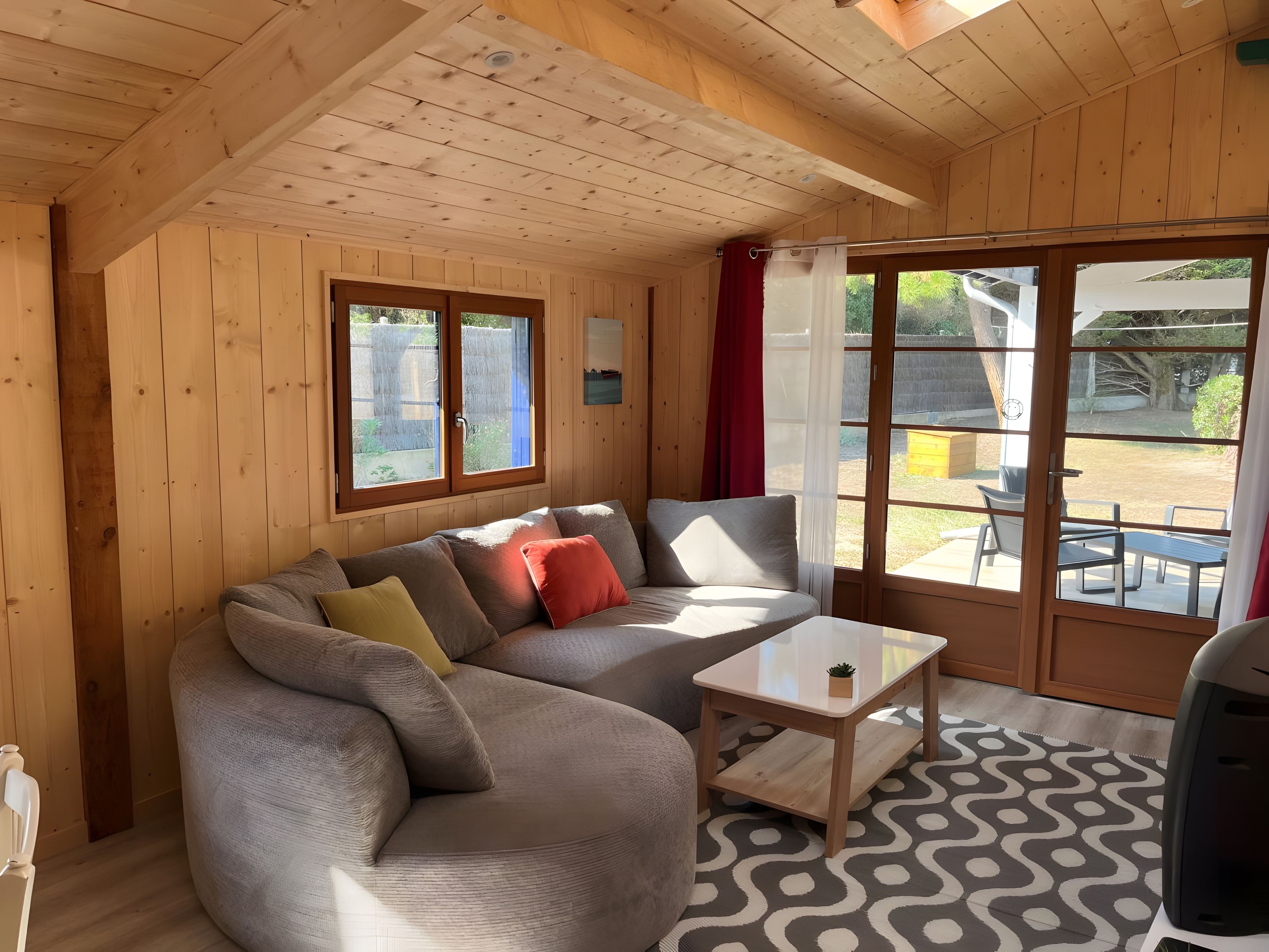 A wooden interior with a sofa, a small table, and a view through a glass door.