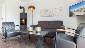 A cozy living room with a fireplace, a sofa, two armchairs, a coffee table, and a floor lamp. - Süderwind 2 - Süderwind 2 - Komplett Renoviertes Mittelhausteil Über 3 Ebenen (Sylt-Ost)