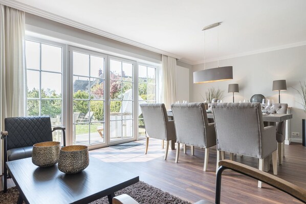 A modern dining area with a large window, a sofa, and a dining table with chairs.