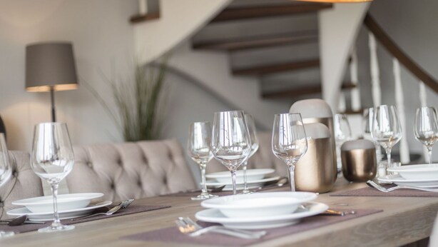 A dining table set with multiple wine glasses, plates, and cutlery, with a modern lamp overhead. - Süderwind 2 - Süderwind 2 - Komplett Renoviertes Mittelhausteil Über 3 Ebenen (Sylt-Ost)