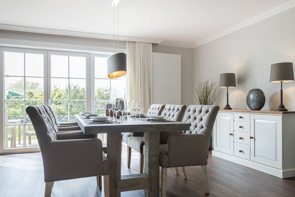 Un comedor con mesa de madera, sillas tapizadas e iluminación colgante.