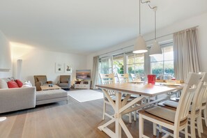Un soggiorno moderno con un divano, poltrone, un tavolo da pranzo con sedie e una TV.