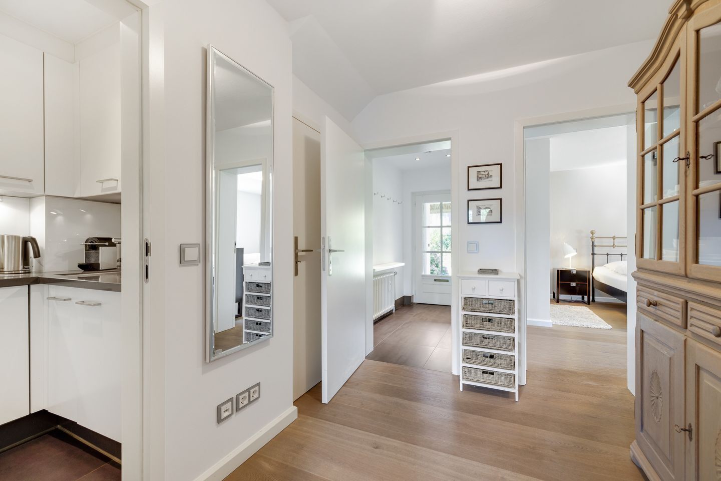 A modern kitchen with white cabinets, a stainless steel kettle, and a white countertop.
