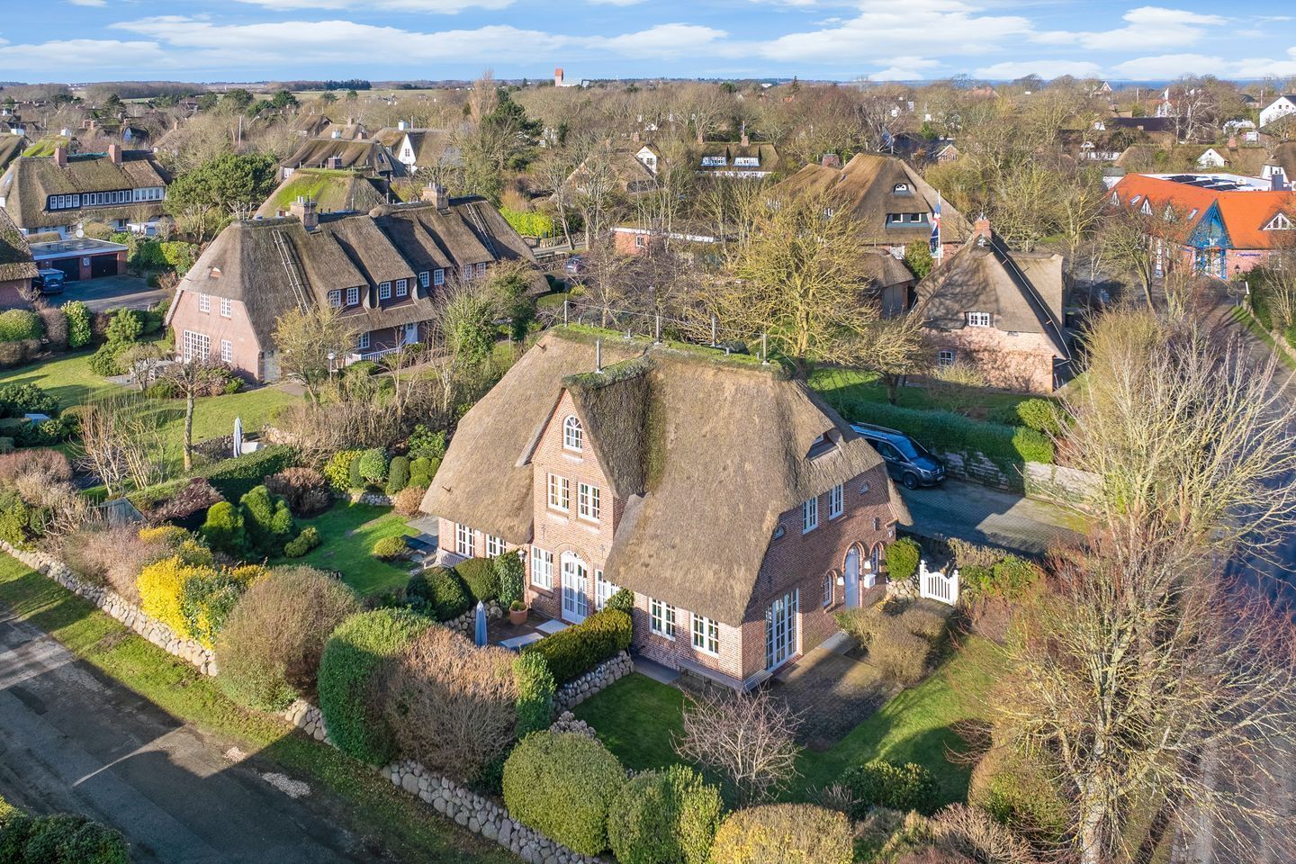 A residential area with houses featuring thatched roofs and brick construction.