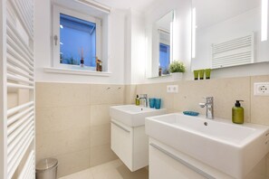 Une salle de bain moderne avec deux lavabos, une fenêtre et un miroir.