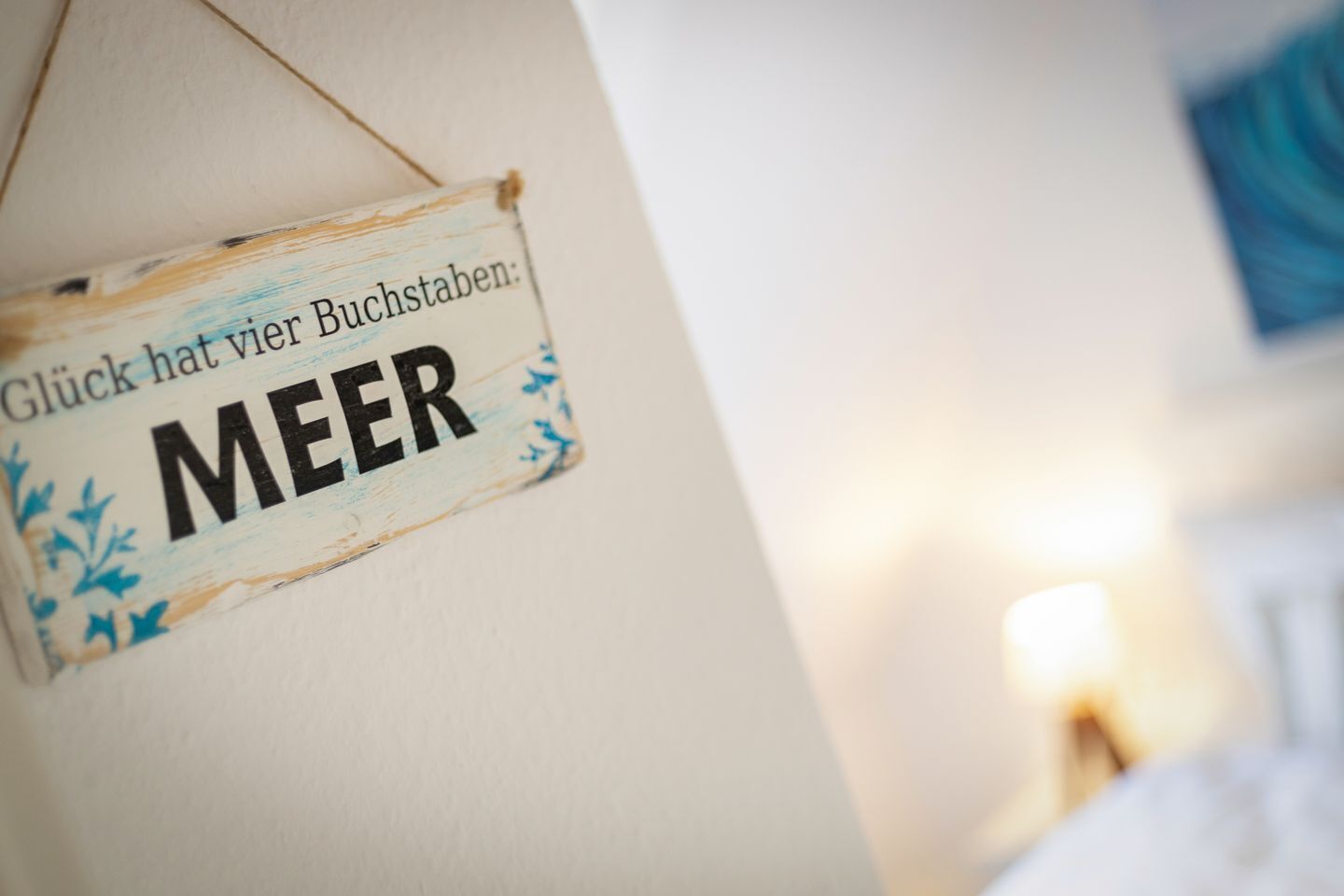 A sign with the text 'Glück hat vier Buchstaben: MEER' on a wall.