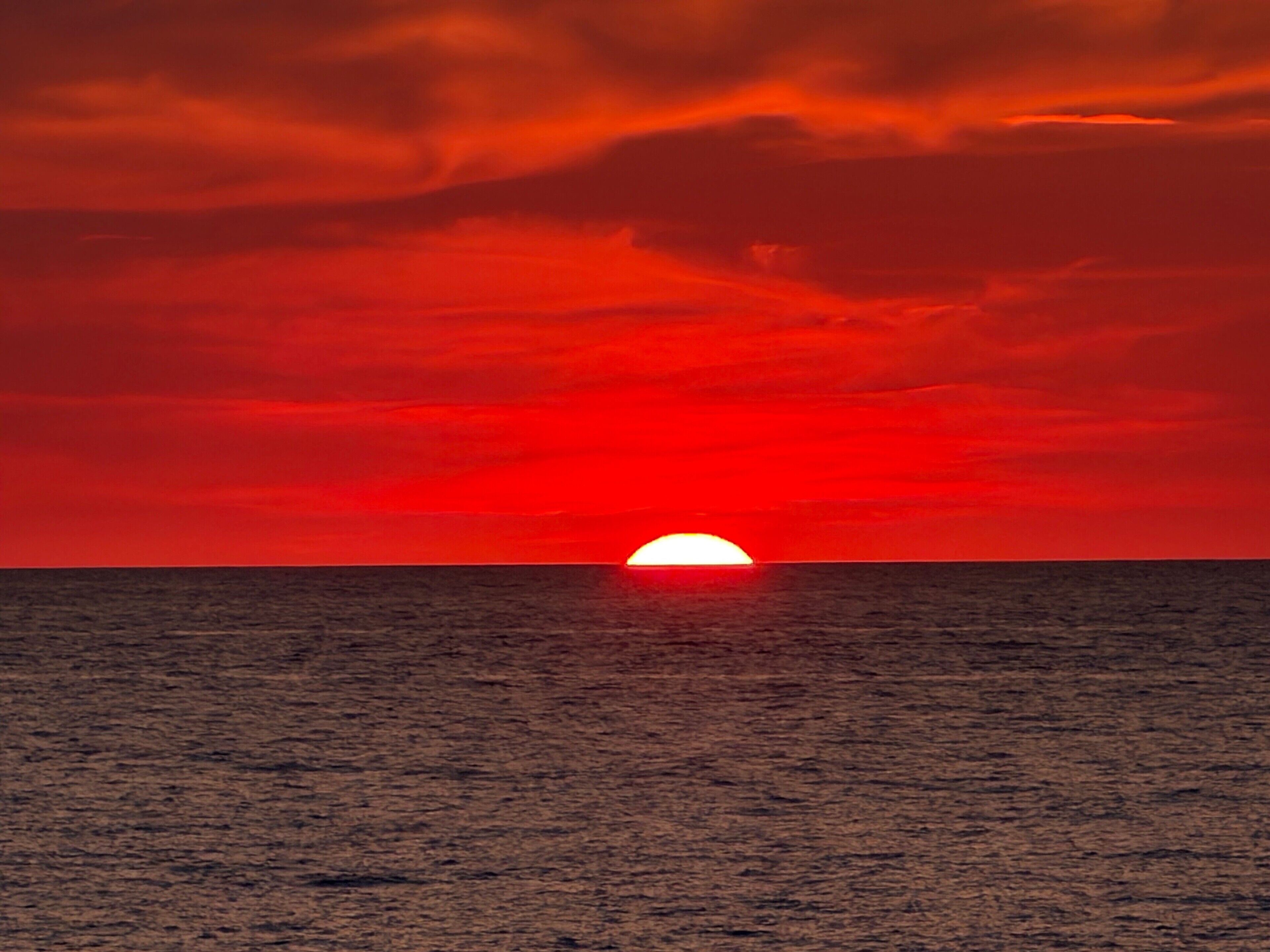 Auringonlasku meren yllä, horisontti on selkeä.