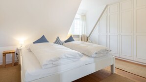 Une chambre à coucher comprenant un lit, une table de chevet, une lampe, une chaise et une armoire.