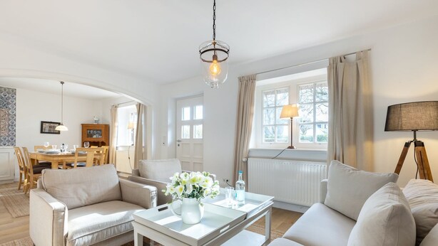 Un salon spacieux comprenant un canapé, des fauteuils, une table basse et un coin repas avec une table et des chaises.