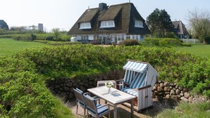 Ein Haus mit einem Strohdach, einer Steinmauer und einem Garten.