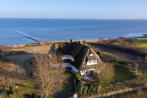 A house with a thatched roof, surrounded by a landscaped garden and a view of the sea. - Kleines Nest - Das Kleine Nest - Obergeschosswohnung mit Unverbautem Blick Aufs (Sylt-Ost)